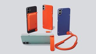 Four of the CMF by Nothing Phone 1s standing on a white table with orange accessories