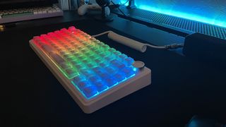 A white keyboard with rainbow RGB keycaps on a black desk